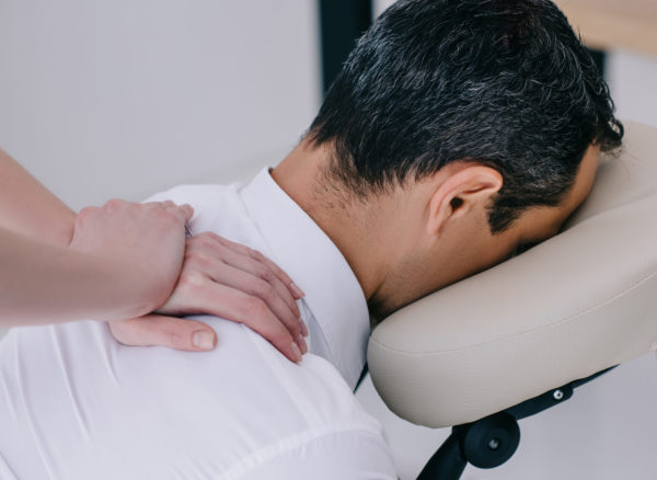 close-up shot of professional masseuse doing seated massage for businessman