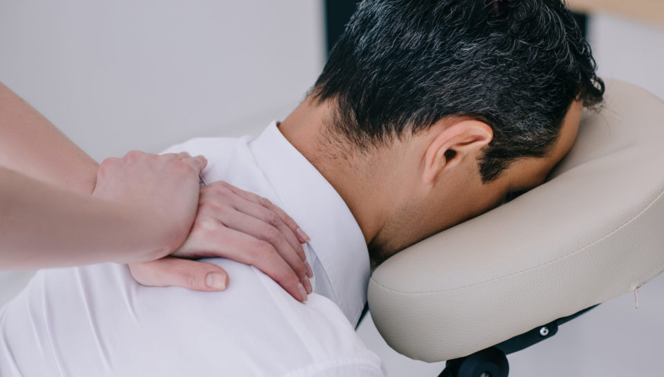 close-up shot of professional masseuse doing seated massage for businessman