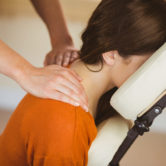 Young woman getting massage in chair in therapy room