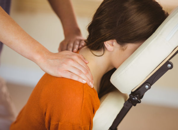 Young woman getting massage in chair in therapy room