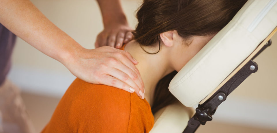Young woman getting massage in chair in therapy room