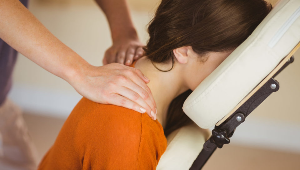 Young woman getting massage in chair in therapy room